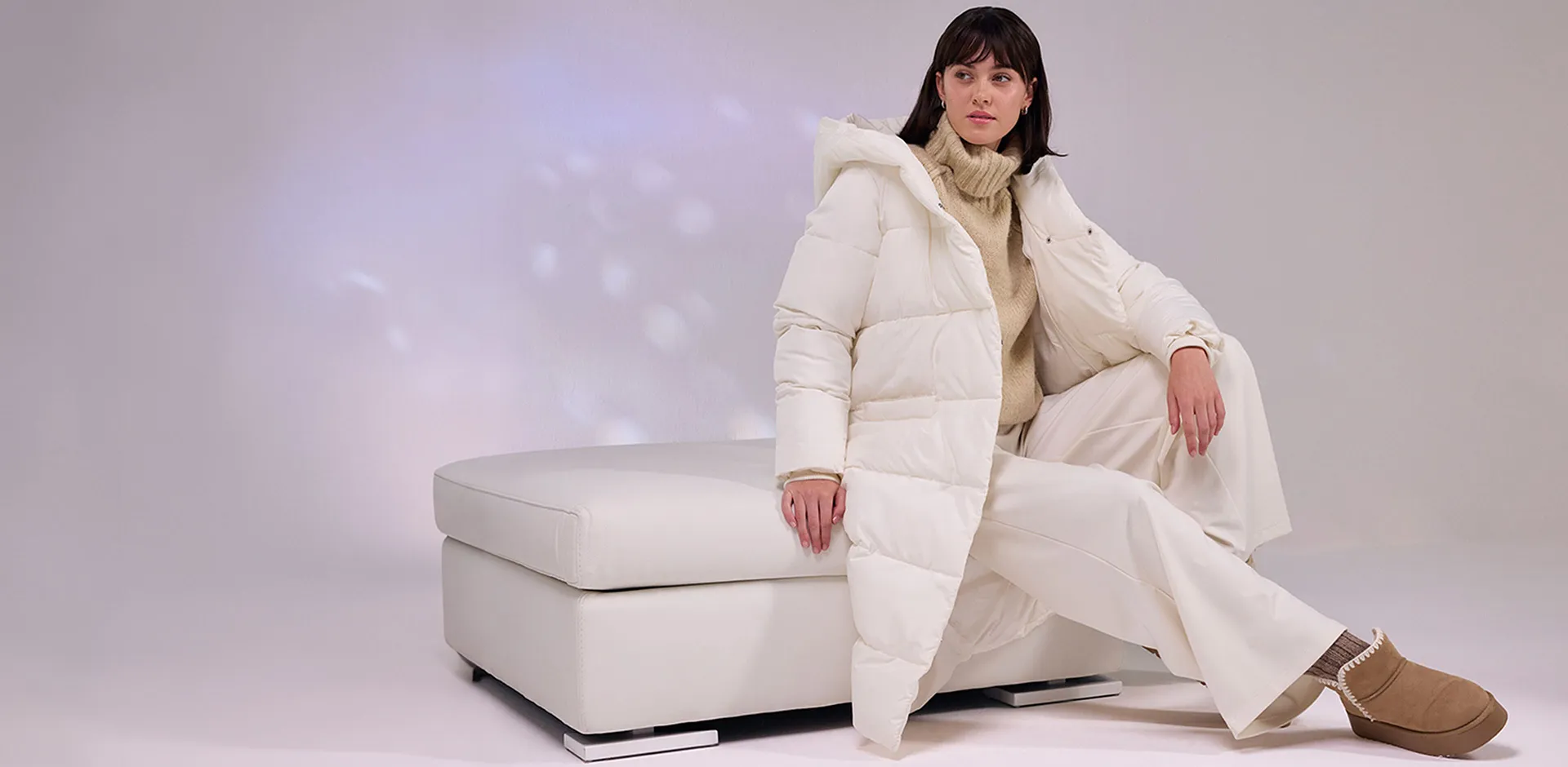 Krémový péřový kabát, bílé kalhoty a měkké boty.
