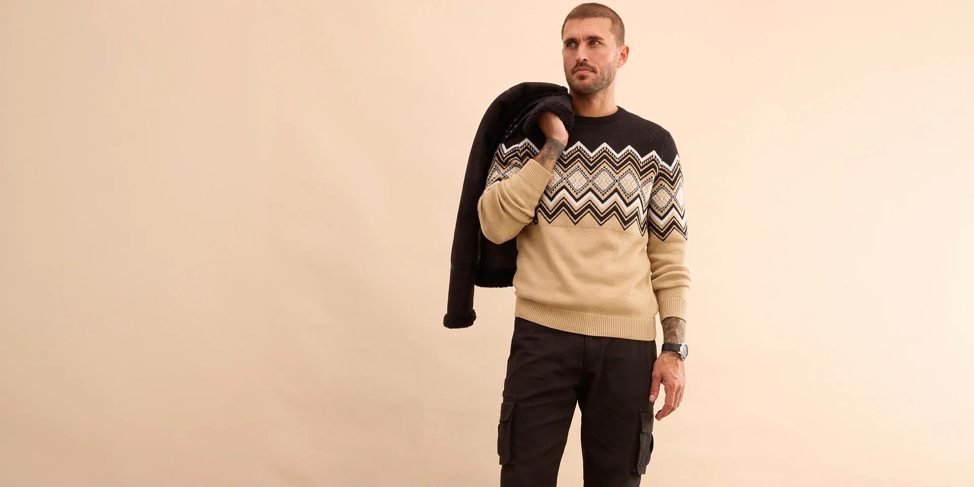 Stylový outfit s černou zimní bundou, vzorovaným svetrem a džínami