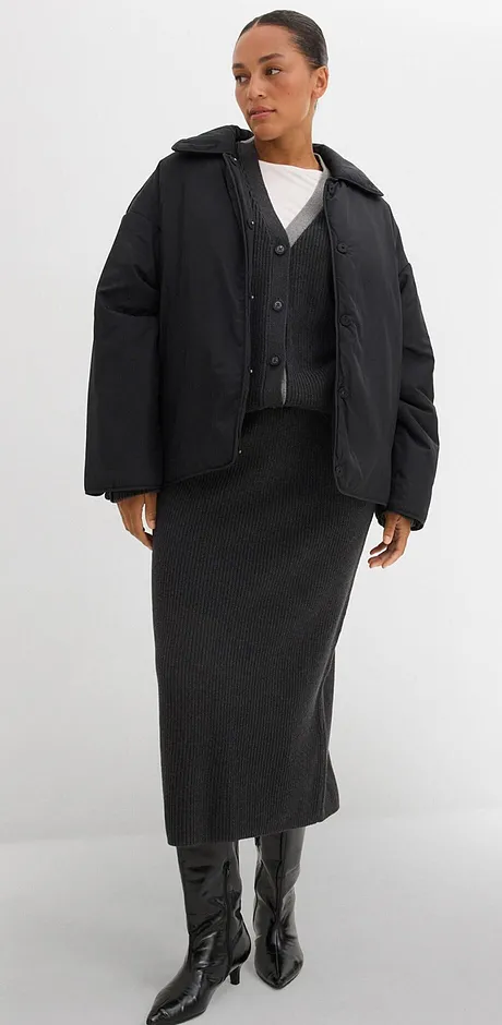 Prošívaná bunda, dlouhá sukně a kožené boty. Pod nimi jednoduchý bílý top.