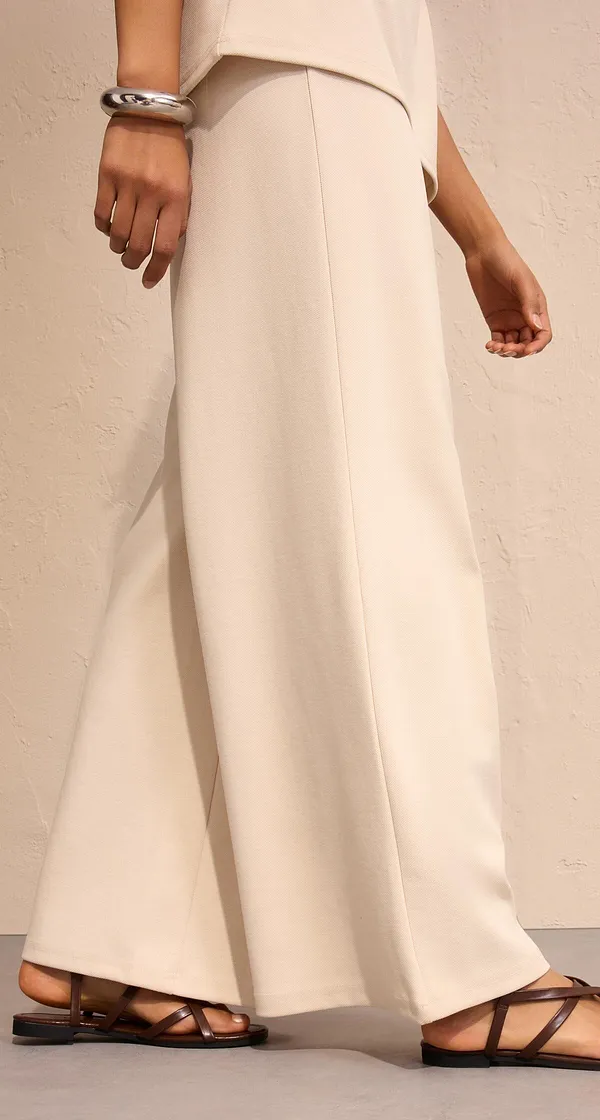 Elegantní široké kalhoty v krémově bílé barvě v kombinaci se sandály.
