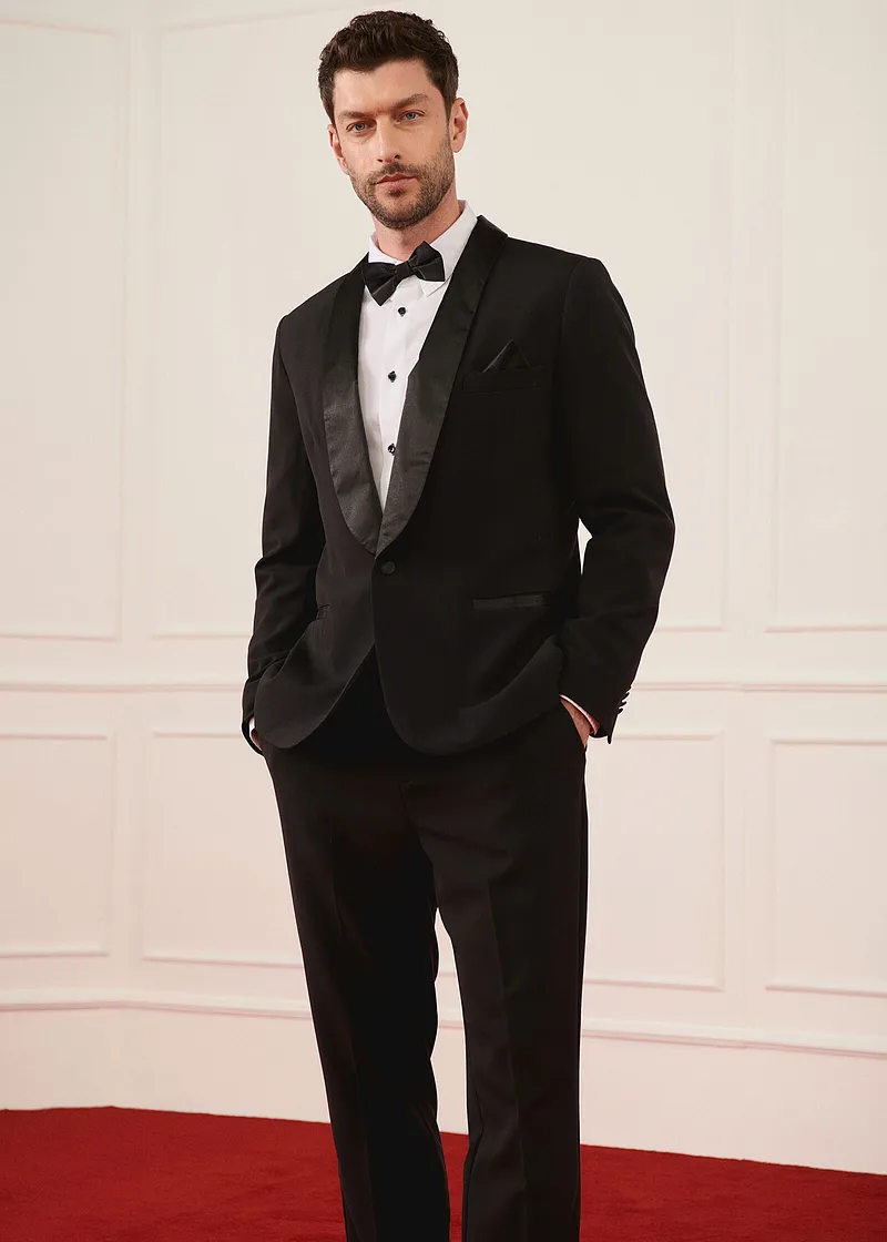 Elegantní černý smoking s motýlkem a bílou košilí pro zvláštní příležitosti.