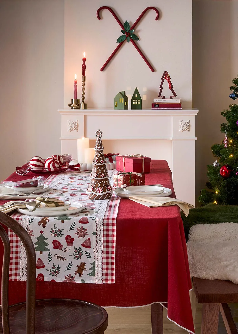 Slavnostní ubrus s vánočním vzorem zdobí prostřený stůl.