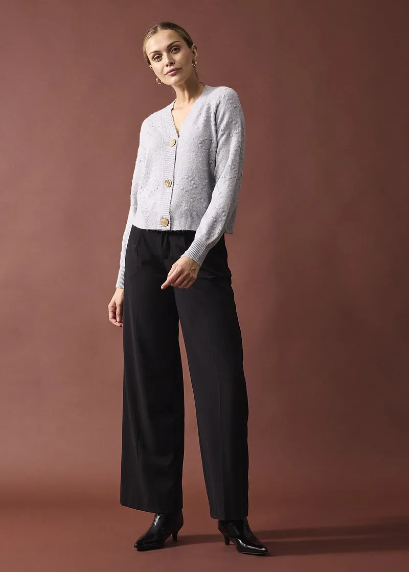 Elegantní bílý svetr s velkými knoflíky.