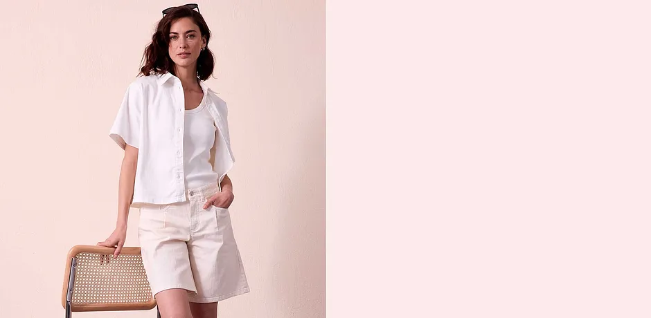 Letní elegantní outfit v bílé barvě: halenka s krátkými rukávy, tričko a kraťasy s kapsami.