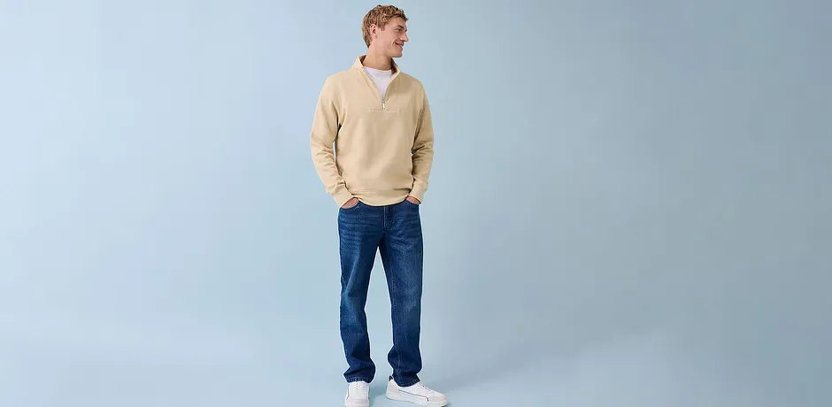 Ležérní look s krémovým svetrem, modrými džíny a bílými teniskami.
