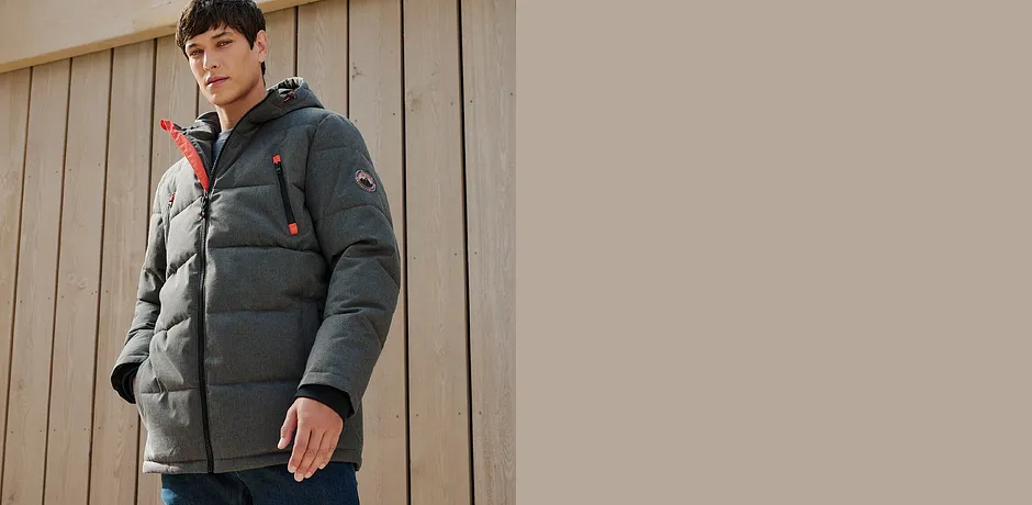 Teplá šedá zimní bunda s kapucí v kombinaci s džíny.