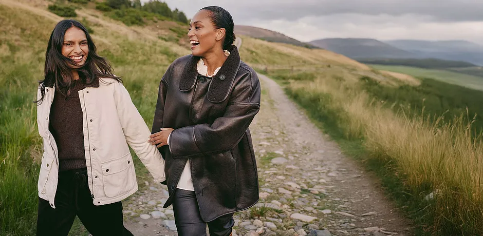 Elegantní hnědý kožený kabát s velkým límcem v kombinaci se světlým topem a tmavými kalhotami.