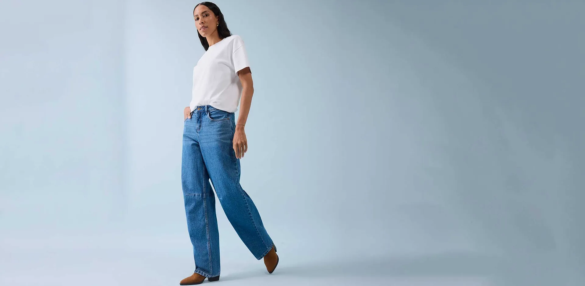 Klasické bílé tričko v kombinaci s širokými džínami a hnědými botami.