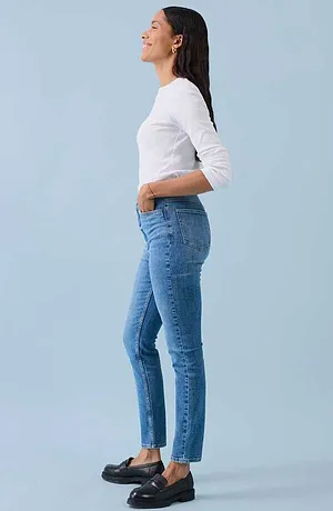 Ležérní look s bílým tričkem s dlouhým rukávem, přiléhavými modrými džíny a černými koženými botami.