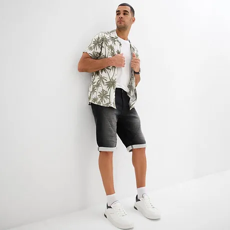 Sommerliches Hawaii-Hemd mit Palmenmuster, weißes T-Shirt, graue Jeans Shorts und weiße Sneakers.