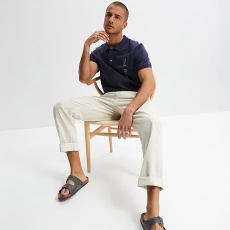 Dunkelblaues Poloshirt mit weißer Hose und grauen Sandalen. Lässiger Sommerlook für den Alltag.