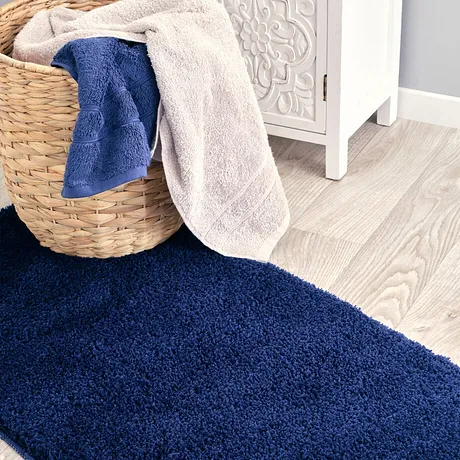 Měkké ručníky v modré a béžové barvě leží v koši na měkkém koberci.