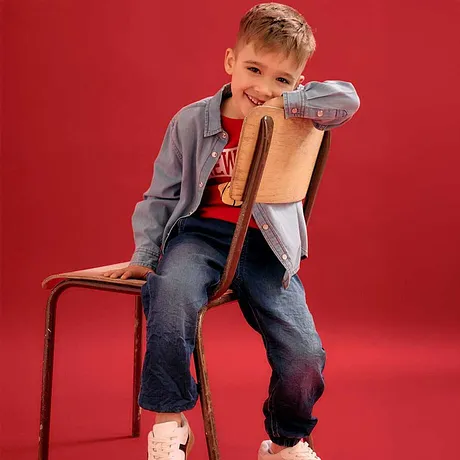 Ležérní look s šedou bundou, červeným tričkem, džíny a bílými teniskami.