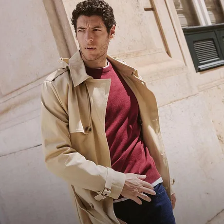 Elegantní béžový kabát přes červený svetr a džíny. Ležérní městský look na podzim.