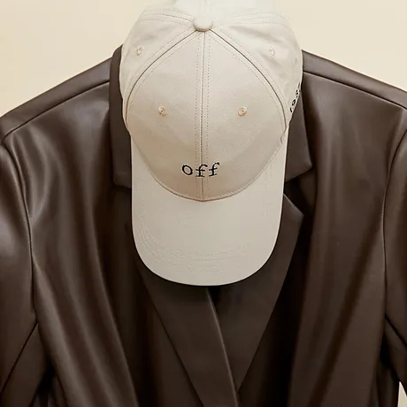 Na ramínku visí béžová čepice a hnědá kožená bunda.