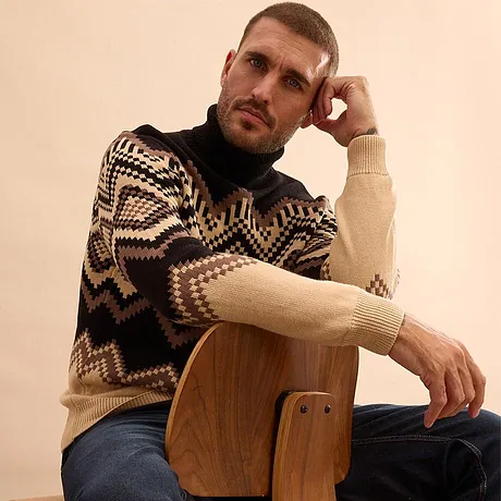 Teplý svetr s geometrickým vzorem a modré džíny.