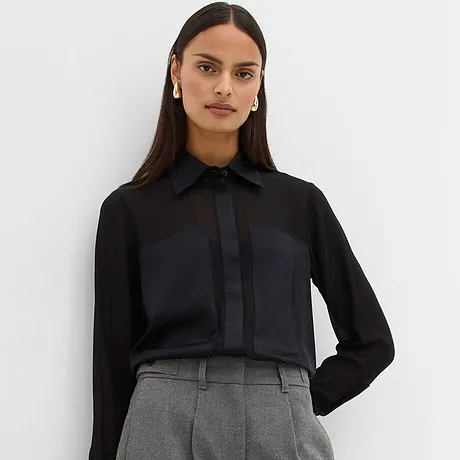 Černá halenka v kombinaci se šedými kalhotami.