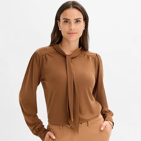 Hnědé tričko s mašlí u krku a dlouhými rukávy.