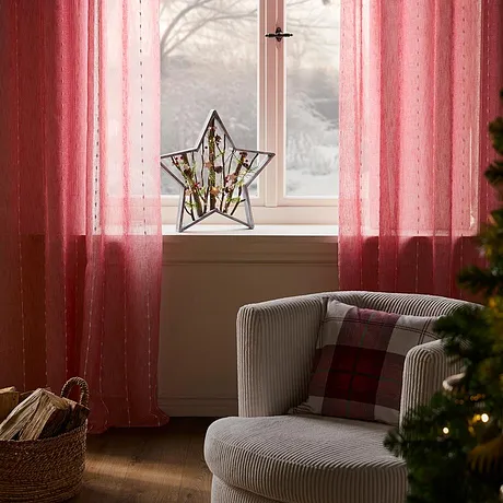Růžové závěsy rámují okno.