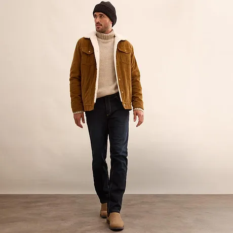 Hnědá bunda, krémový rolák a tmavé džíny.