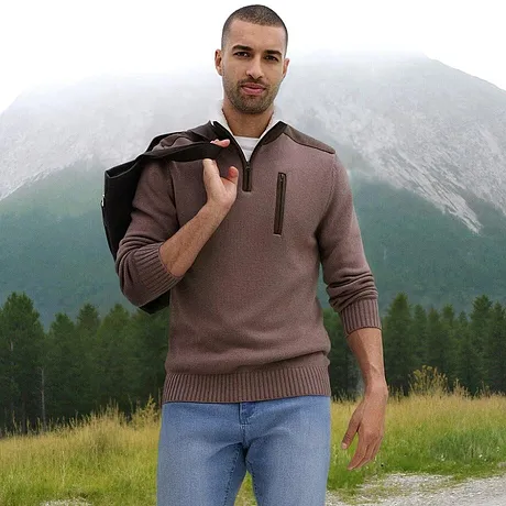 Hnědý svetr se zipem a límcem v kombinaci se světlými džínami.