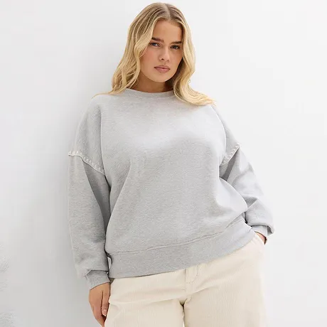 Šedá mikina v kombinaci se světlými kalhotami.