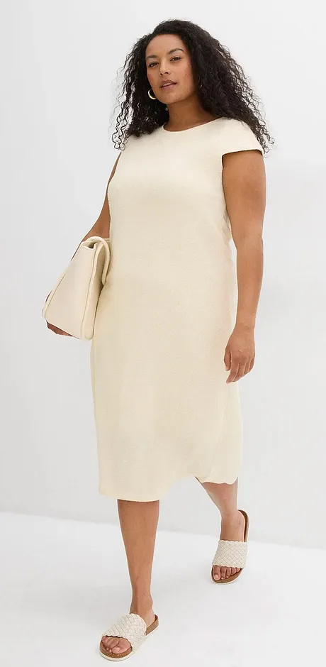 Schlichtes cremefarbenes Kleid mit kurzen Ärmeln, kombiniert mit hellen Sandalen und einer passenden Handtasche.
