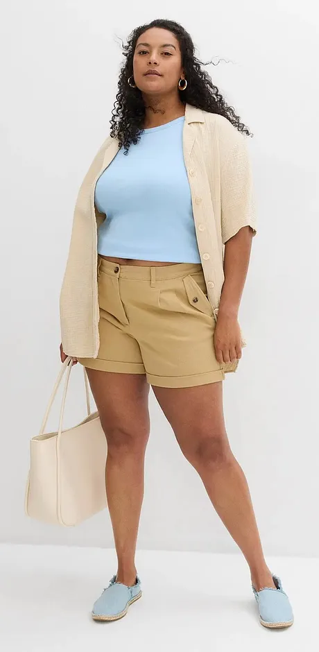 Sommerliches Outfit mit hellblauem Top, beigefarbenem Cardigan, khakifarbenen Shorts und passenden Schuhen.