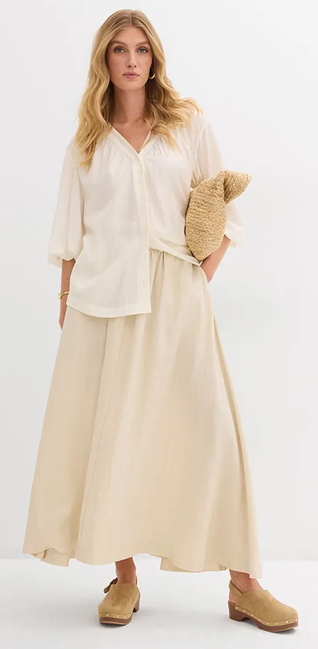 Vzdušný, krémově zbarvený letní outfit s volnou blůzou a dlouhou sukní.