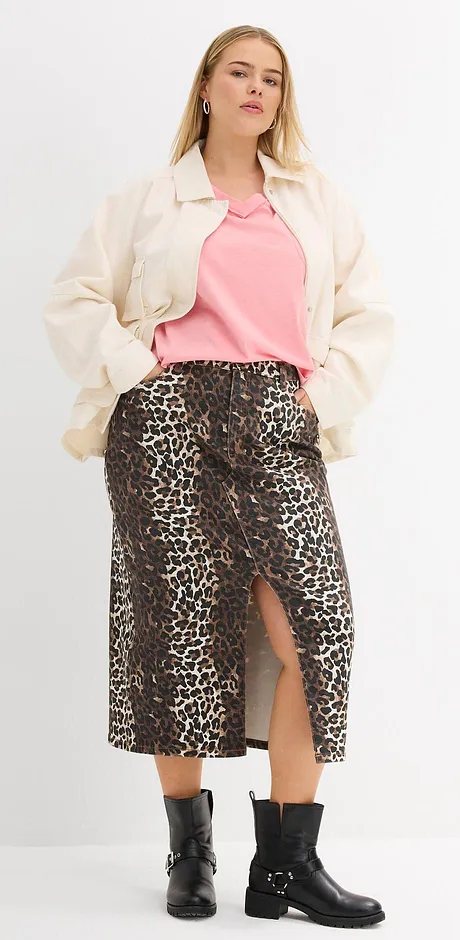 Krémová bunda, růžové tričko, sukně s leopardím vzorem a černé boty tvoří stylový look.