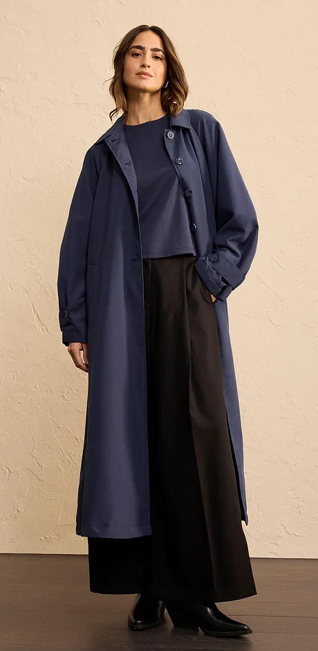 Elegantní dlouhý kabát v tmavě modré barvě, kombinovaný s širokými kalhotami a jednoduchým topem.