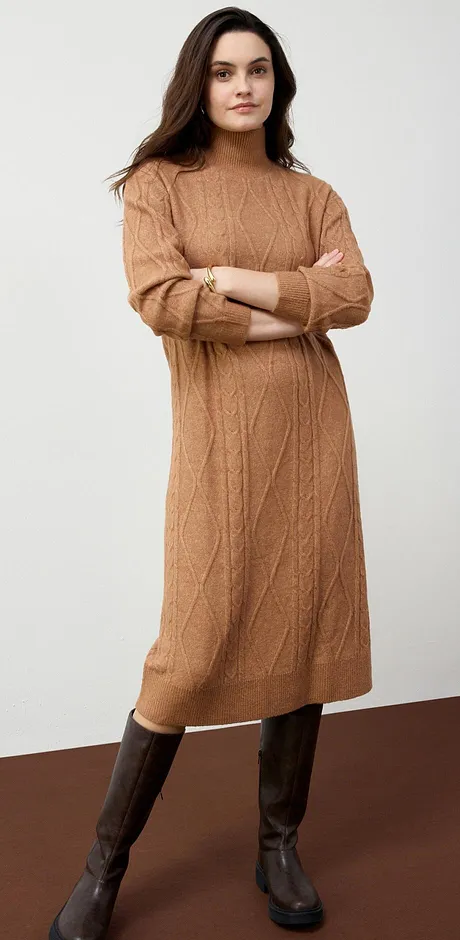 Teplé pletené šaty v barvě velbloudí srsti v kombinaci s hnědými koženými botami vyzařují podzimní eleganci.