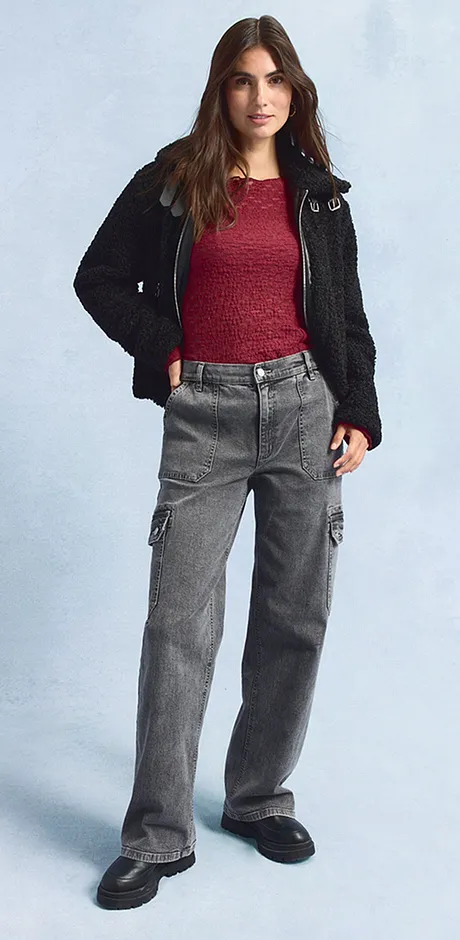 Černá bunda, červený svetr, široké šedé džíny a tmavé boty.