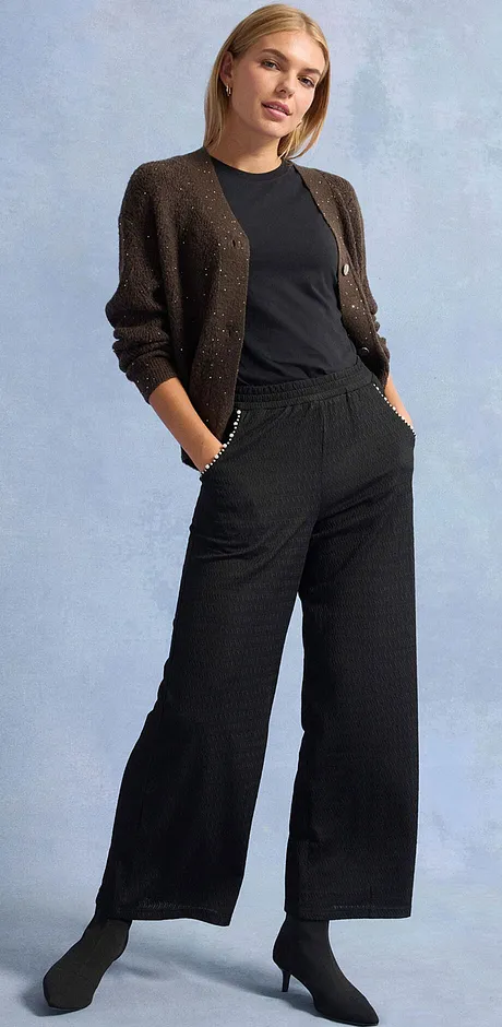 Černé kalhoty, tričko a třpytivý svetr.