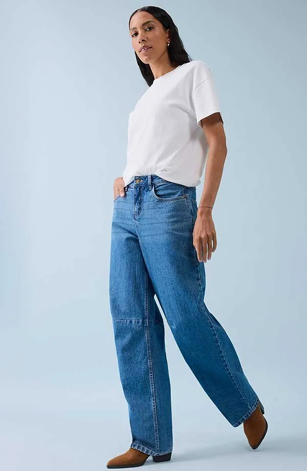 Klasické bílé tričko v kombinaci s širokými džínami a hnědými botami.