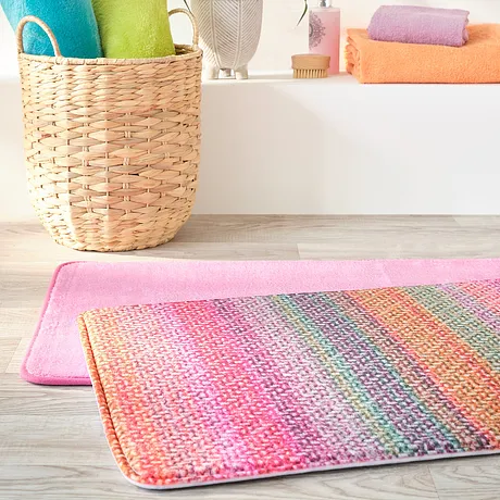 Bunte Handtücher und eine farbenfrohe Badematte bringen Frische ins Badezimmer.