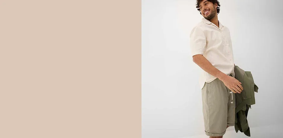 Luftiges weißes Hemd mit Kragen, beige Shorts und grüne Jacke für entspannten Sommerlook.