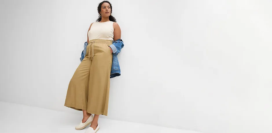 Entspannter Sommerlook: Weite beigefarbene Hose, weißes Top und lockere blaue Jeansjacke.