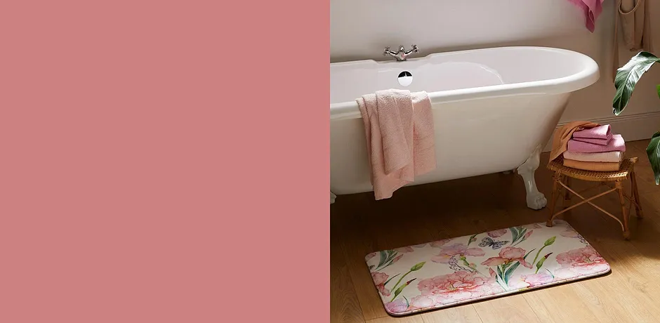 Koupelnu s bílou vintage vanou zdobí čerstvé ručníky a květinová koupelnová předložka.