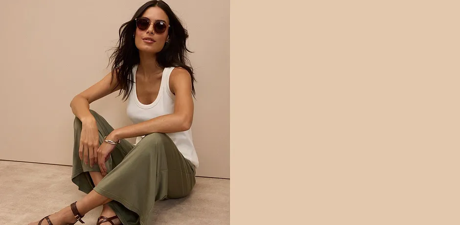 Bílé tílko, olivově zelené kalhoty a hnědé sandály – ležérní letní look se slunečními brýlemi.