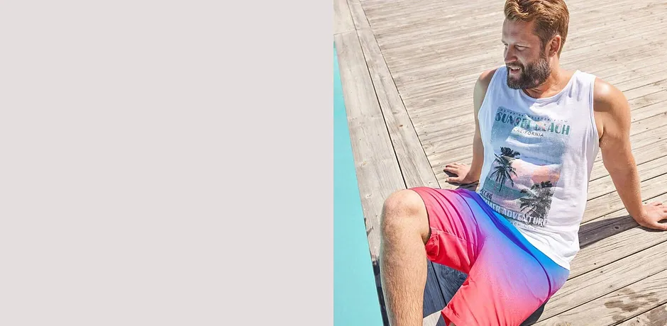 Weißes Tank-Top und bunte Badeshorts in Pink und Blau für Pool und Strand.