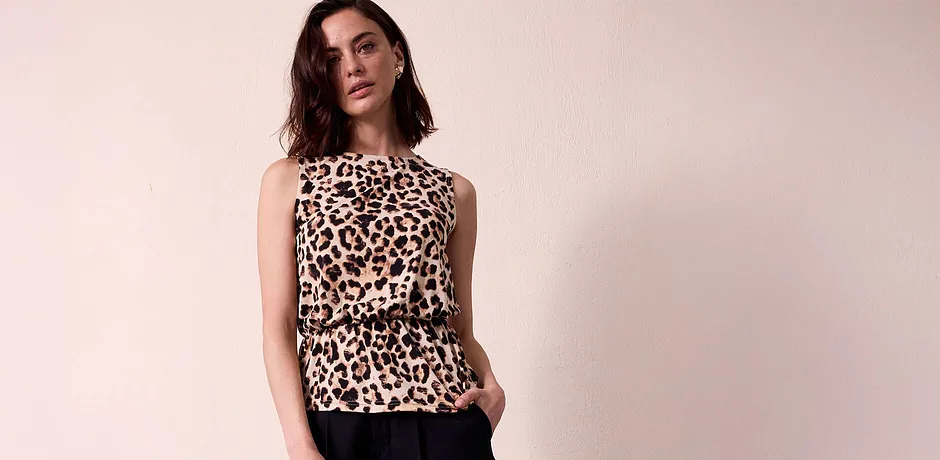 Bezrukávová blůza s leopardím vzorem, elegantní a stylová. Černé kalhoty jako kontrast k divokému potisku.