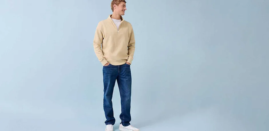Ležérní look s krémovým svetrem, modrými džíny a bílými teniskami.