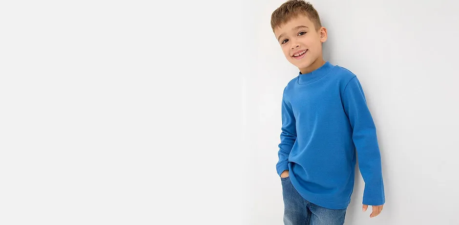 Modrý svetr s dlouhými rukávy a klasické modré džíny.