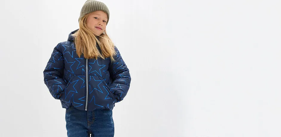 Prošívaná modrá bunda, džíny a měkká zelená čepice.