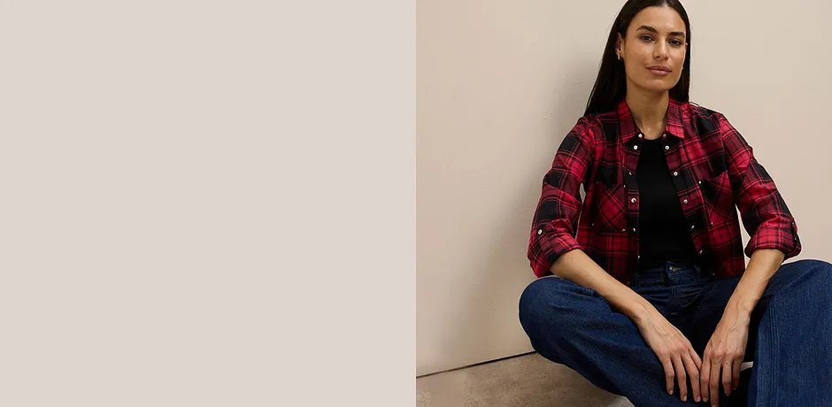 Červeno-černá kostkovaná košile přes černý top, kombinovaná s klasickými džíny.