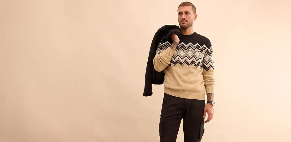 Stylový outfit s černou zimní bundou, vzorovaným svetrem a džínami