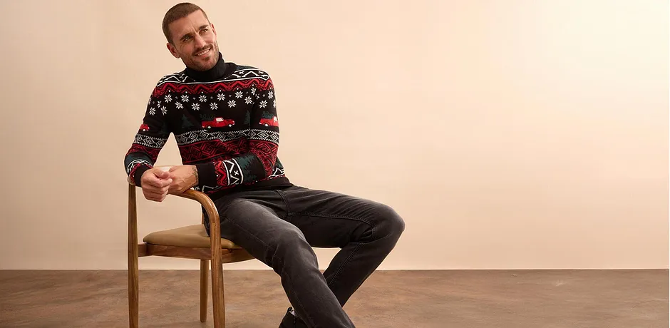 Vánoční svetr s barevným vzorem, k tomu tmavé džíny. 