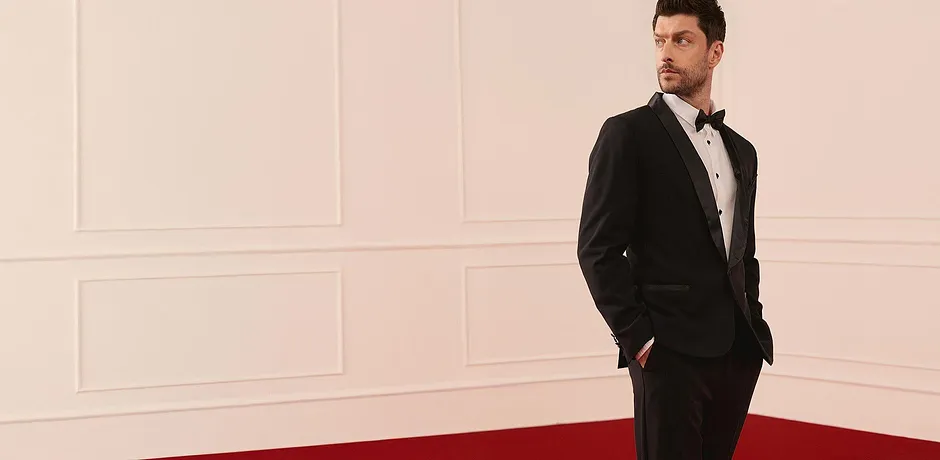 Elegantní černý smoking s bílou košilí a motýlkem pro slavnostní příležitosti.