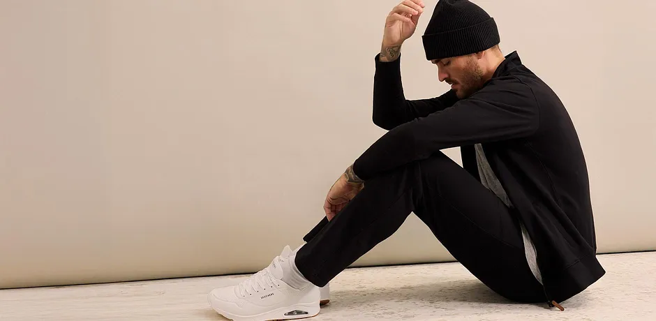 Černá tepláková souprava s čepicí a bílými teniskami.